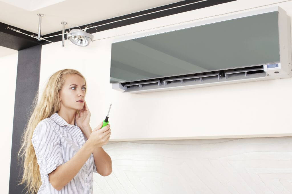 The girl is holding a tool in her hand and looking at the Benefits of installing a zoned air conditioner