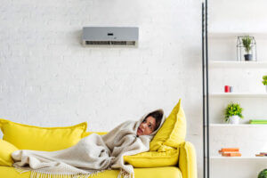 The girl is shivering from the cold air of the air conditioner. Effects of air conditioners on health